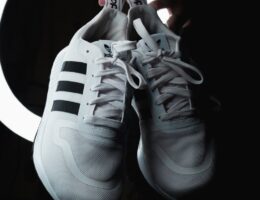 Hand hält ein Paar schwarz-weiße Adidas Campus 00 Schuhe