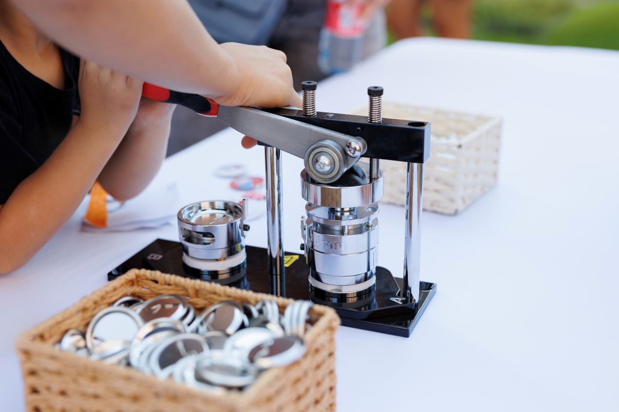 Eine Person verwendet eine Buttonmaschine zur Herstellung von individuellen Buttonrohlingen