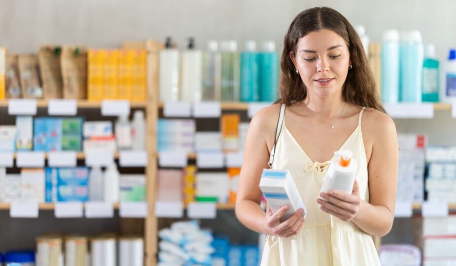 Frau haelt zwei Kosmetikprodukte im Drogeriemarkt und vergleicht Inhaltsstoffe – Orientierungshilfe durch Bdr Kosmetik