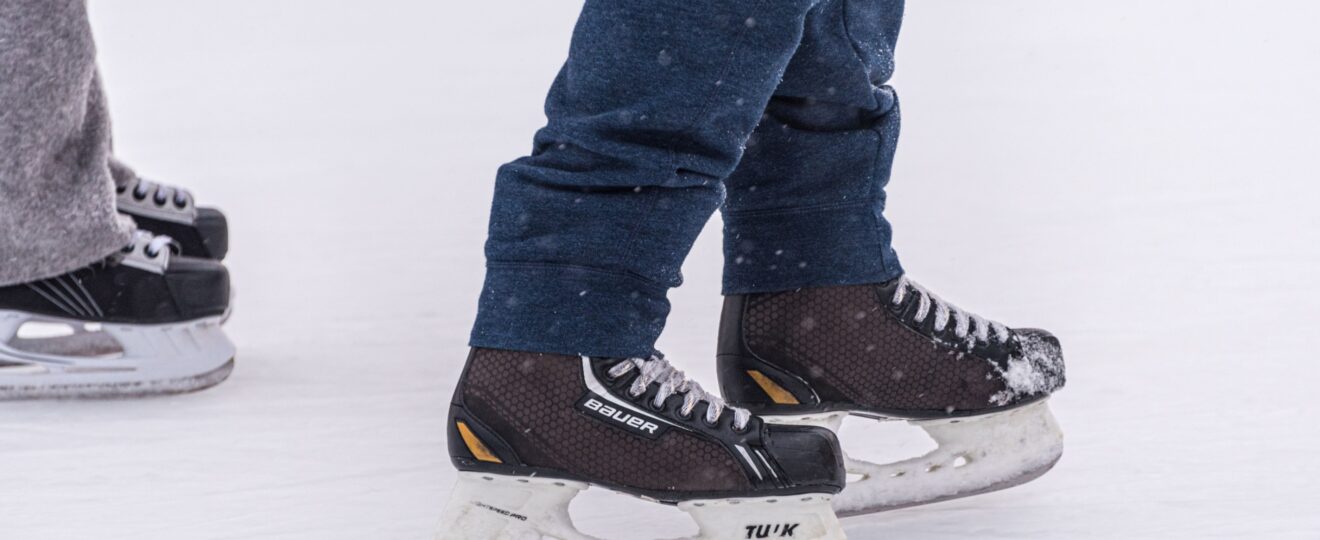 Nahaufnahme von zwei Personen mit Schlittschuhen auf dem Eis
