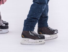 Nahaufnahme von zwei Personen mit Schlittschuhen auf dem Eis