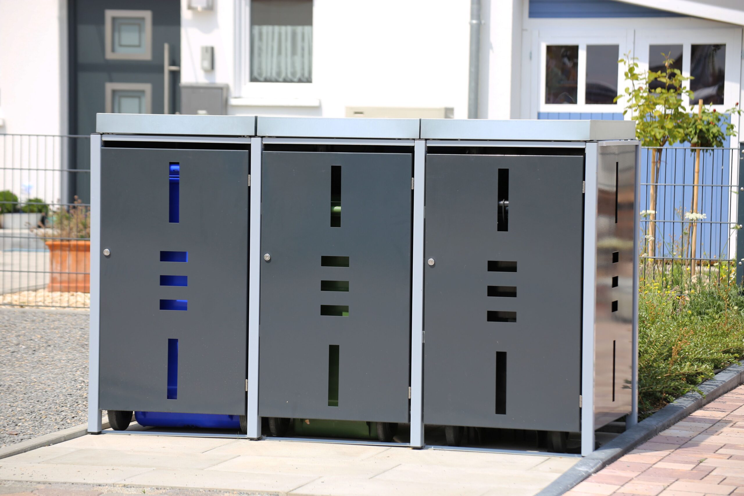 Mülltonnenbox mit drei Fächern in modernem Design vor Wohnhaus