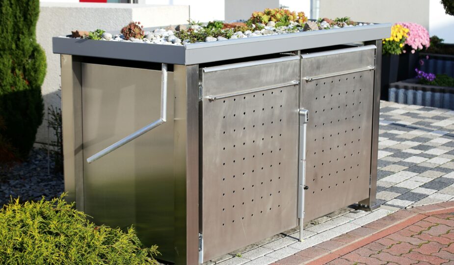 Mülltonnenbox aus Edelstahl mit Pflanzdach in moderner Vorgartengestaltung
