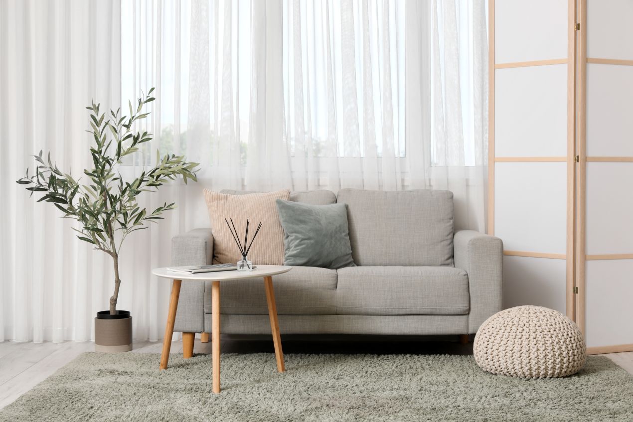 Kleines Wohnzimmer mit Sofa, Paravent aus Holzpaneelen und Pflanze – elegante Lösung zur Raumtrennung