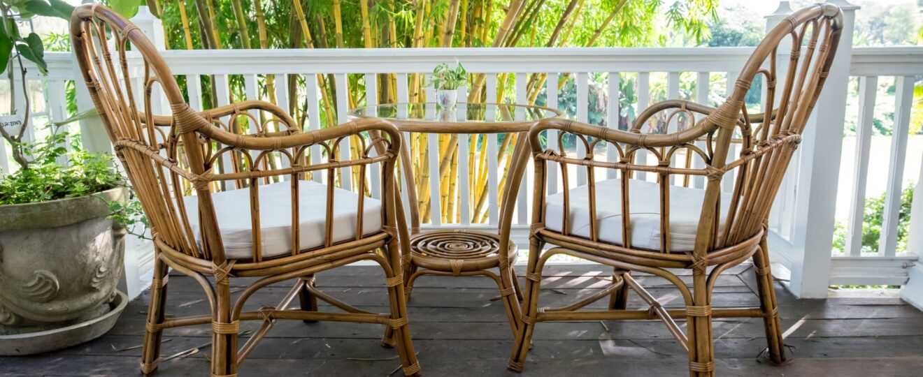 Zwei Rattan-Stühle mit Tisch auf einer Terrasse vor Bambus-Pflanzen – idealer Ort für entspannte Stunden im Freien