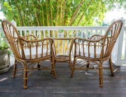 Zwei Rattan-Stühle mit Tisch auf einer Terrasse vor Bambus-Pflanzen – idealer Ort für entspannte Stunden im Freien
