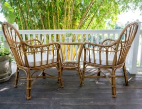 Zwei Rattan-Stühle mit Tisch auf einer Terrasse vor Bambus-Pflanzen – idealer Ort für entspannte Stunden im Freien