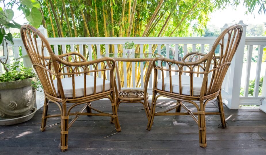 Zwei Rattan-Stühle mit Tisch auf einer Terrasse vor Bambus-Pflanzen – idealer Ort für entspannte Stunden im Freien