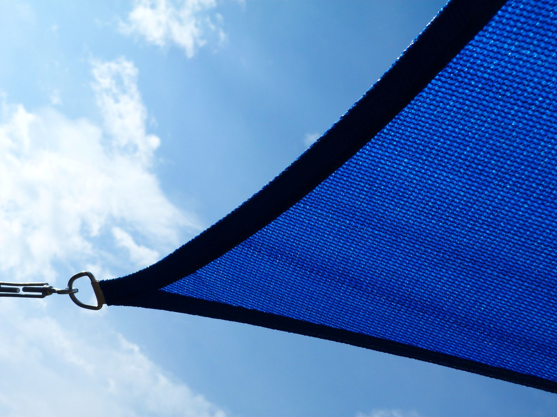 Detailaufnahme eines blauen Sonnensegels, das unter freiem Himmel gespannt ist – modernes Design und zuverlässiger UV-Schutz.