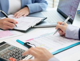 Team erstellt Kostenanalyse mit Tabellen und Laptop | Staubsauger Industrie