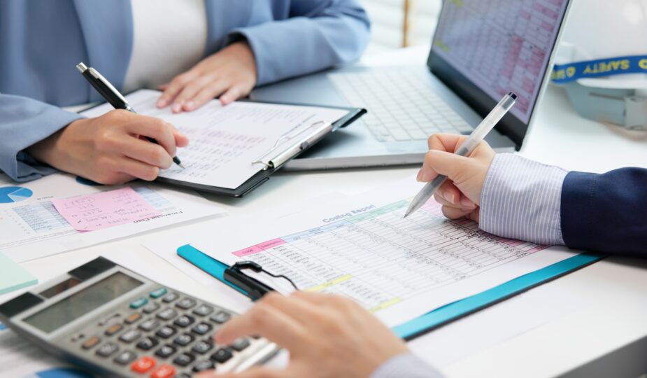 Team erstellt Kostenanalyse mit Tabellen und Laptop | Staubsauger Industrie